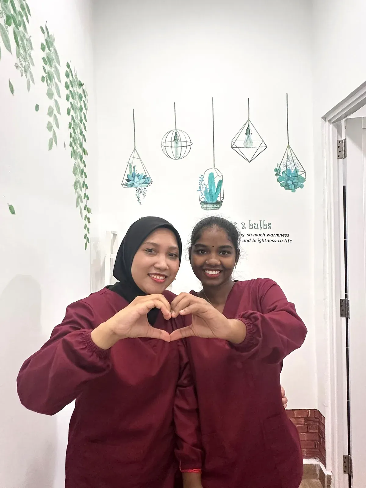 Two Lau & Su Partners Dental team members making a heart shape with their hands, the friendly welcome patients get in Bukit Jalil