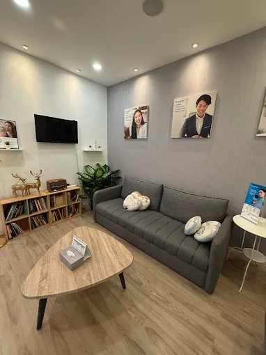 Calm waiting lounge with sofa seating and reading shelf at our Bukit Jalil dental clinic, designed to keep patients relaxed before treatment