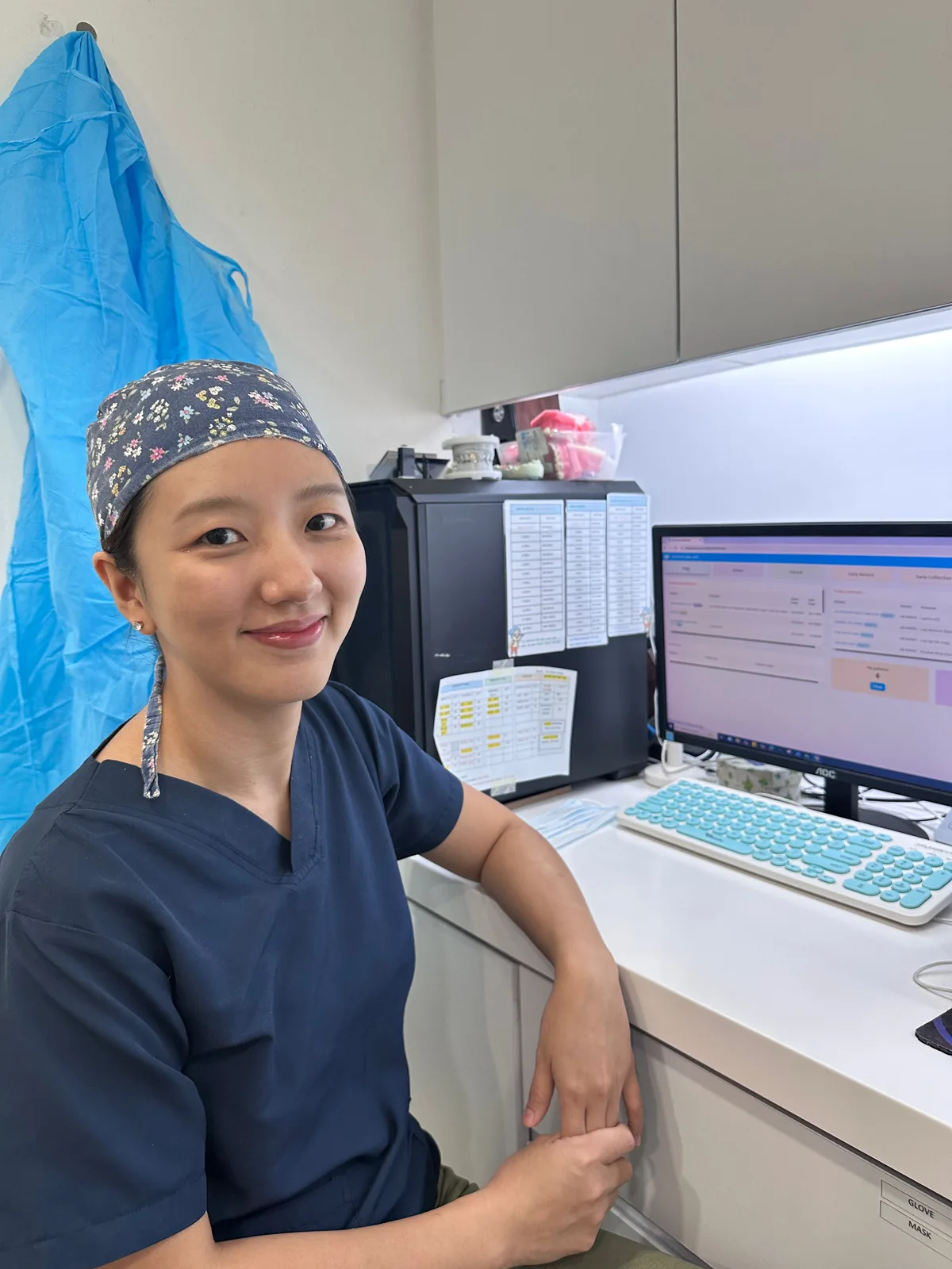 Dr. Khoo Cher Xing in a surgical cap reviewing digital patient records at the treatment room workstation in Bukit Jalil