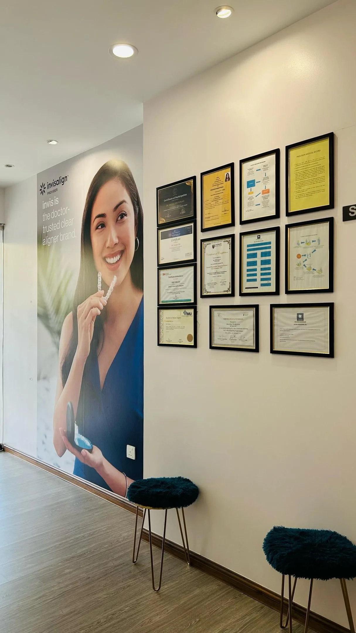 Invisalign provider wall graphic beside framed certificates at our Bukit Jalil clinic, showing accredited clear aligner experience