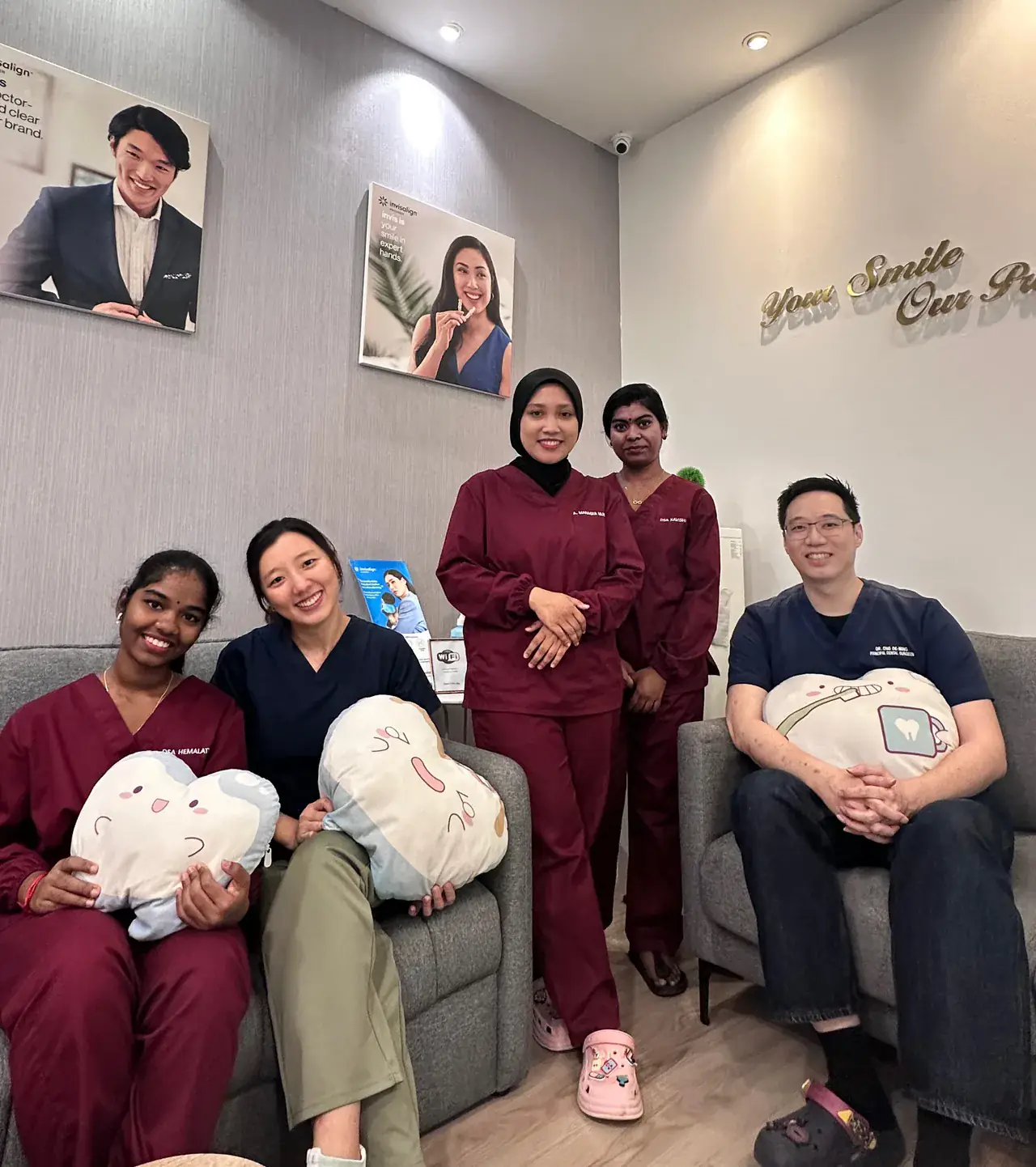 The Lau & Su Partners Dental team in the Bukit Jalil clinic lounge, five dentists and staff smiling on the sofas with tooth-shaped cushions